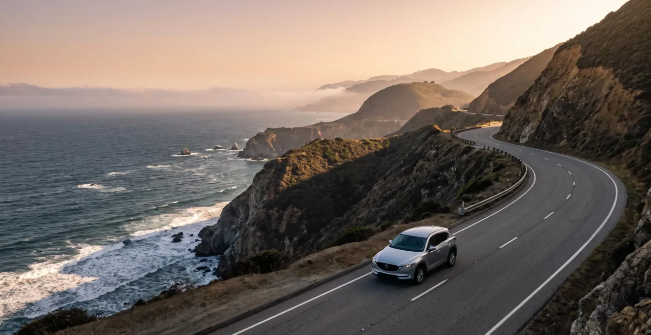 A car driving along a dramatic cliffside coastal highway at golden hour, symbolizing a multi-state US road trip