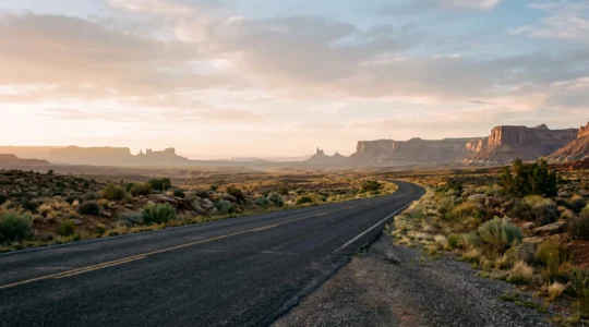 A solitary open highway stretching through a vast American desert landscape at golden hour, symbolizing a journey beyond typical tourist traps