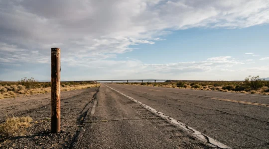 An empty two-lane historic highway stretching toward the horizon under a vast American sky, symbolizing the enduring spirit of Route 66 in the modern era